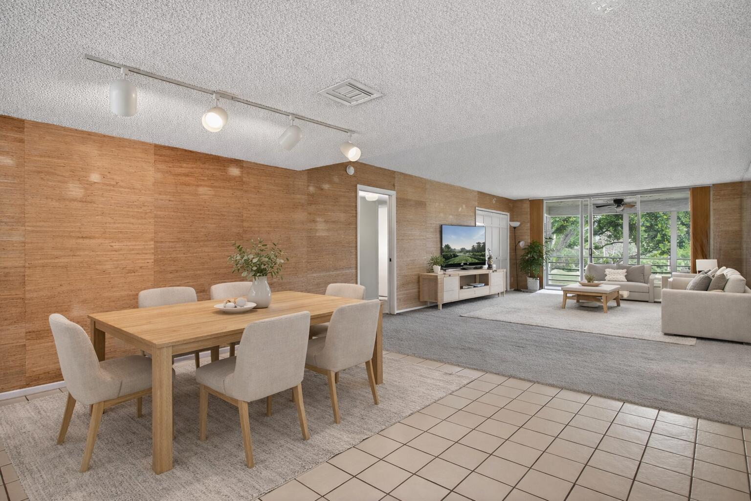 An open-concept living and dining area features wood-paneled walls, tile flooring, and carpeted zones — 800 Cypress Boulevard # 204a, Pompano Beach FL 33069, POMPANO BEACH, FL