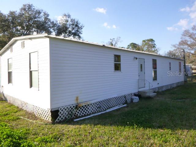 The exterior of a white mobile home with lattice skirting sits on a grassy lot — 6616 MANGROVE DRIVE, WESLEY CHAPEL, FL