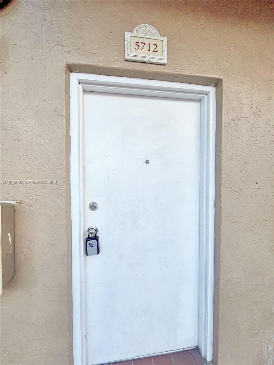 A white exterior door with a lockbox and a house number sign above it — 5712 W 25th Ct # 5712, Hialeah FL 33016, HIALEAH, FL