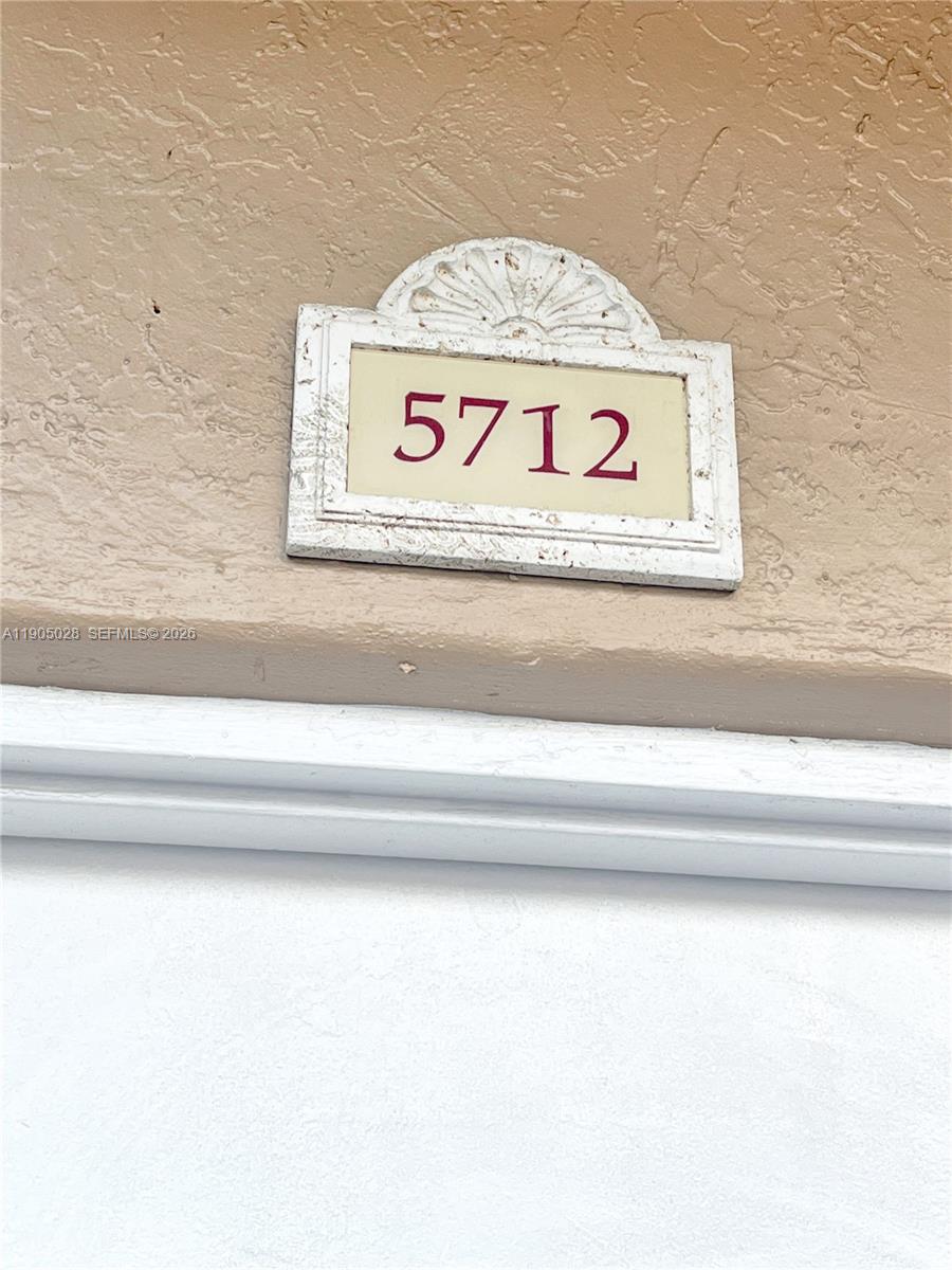 A white address plaque with the number 5712 is mounted on a beige exterior wall — 5712 W 25th Ct # 5712, Hialeah FL 33016, HIALEAH, FL