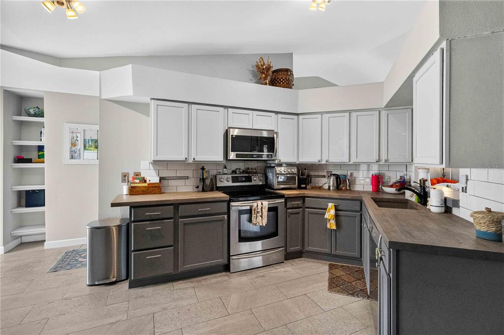 A kitchen features two-toned gray and white cabinetry, stainless steel appliances, and wood-look countertops — 1703 LARABIE COURT, BRANDON, FL
