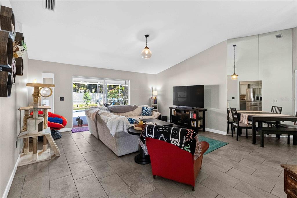 A living room with tile floors, a sectional sofa, a television, and a dining area — 1703 LARABIE COURT, BRANDON, FL