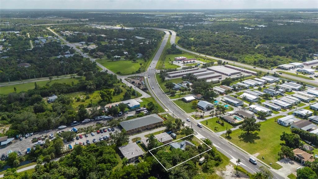 An aerial view shows a residential property outlined in white near a multi-lane highway — 25158 MARION AVENUE, PUNTA GORDA, FL