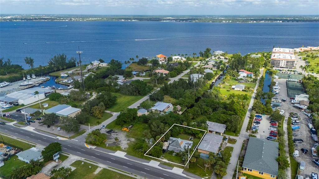 An aerial view shows a house outlined in white situated near a road and waterfront — 25158 MARION AVENUE, PUNTA GORDA, FL