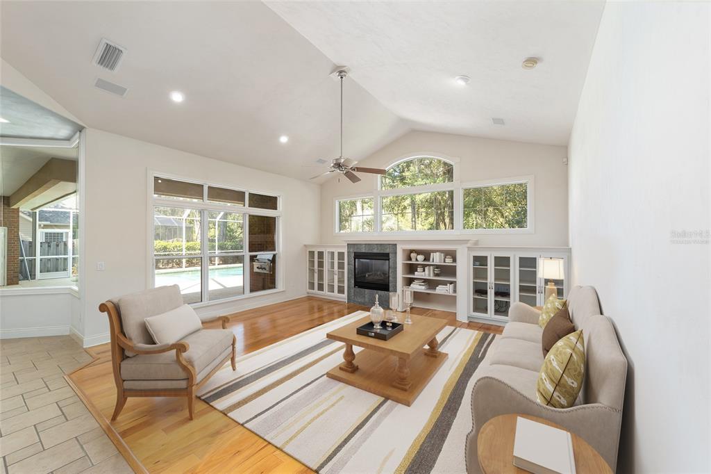 A living room features hardwood floors, a fireplace with built-in shelving, and large windows — 5604 NW 52ND AVENUE, GAINESVILLE, FL
