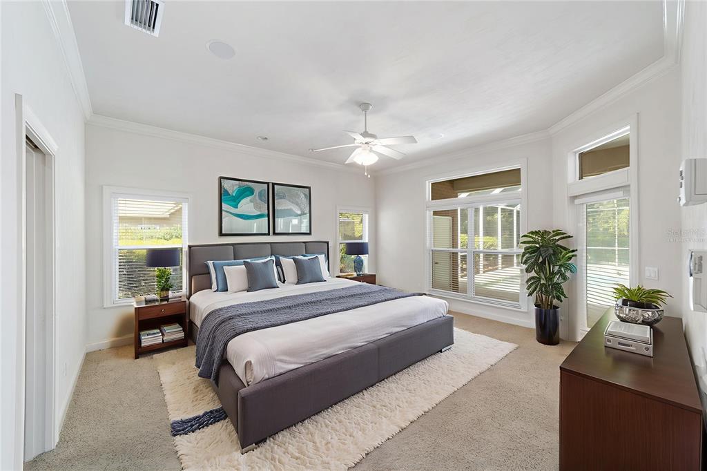 A bedroom features a king-sized bed, carpeted flooring, large windows, and a ceiling fan — 5604 NW 52ND AVENUE, GAINESVILLE, FL