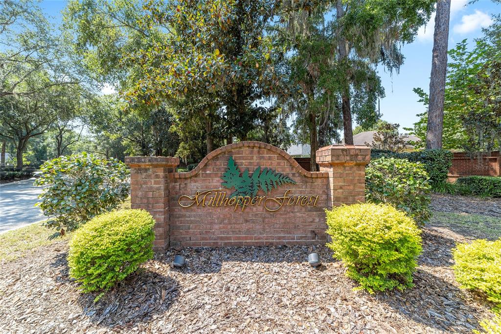 A brick entrance sign for Millhopper Forest stands surrounded by trees and landscaping — 5604 NW 52ND AVENUE, GAINESVILLE, FL