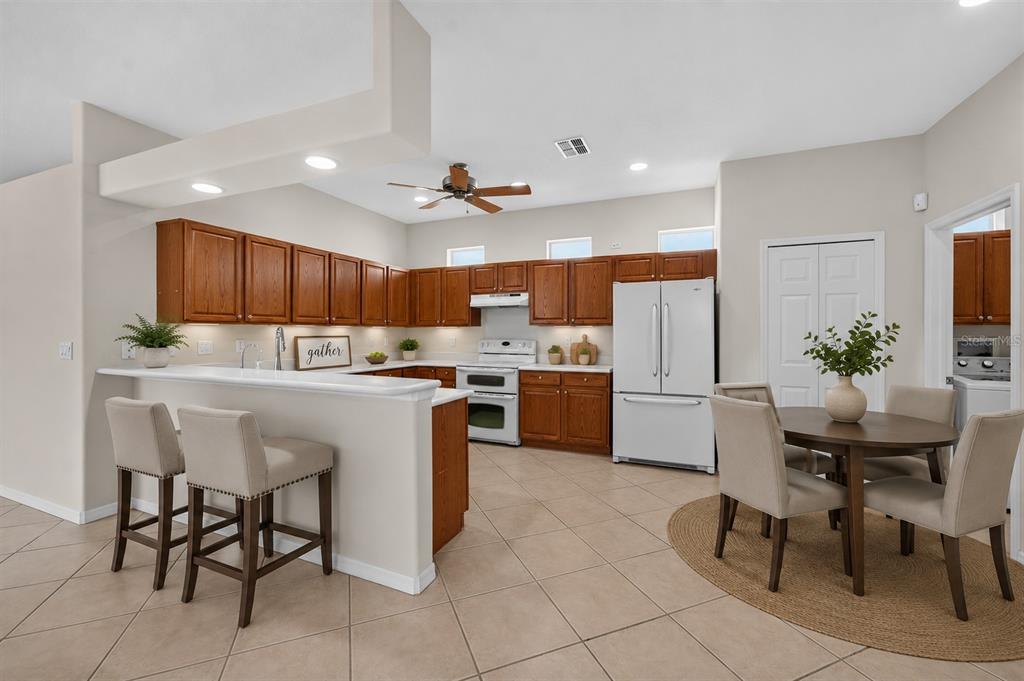 A kitchen with wood cabinets, white appliances, a breakfast bar, and a dining area — 20931 DIAMONTE DRIVE, LAND O LAKES, FL