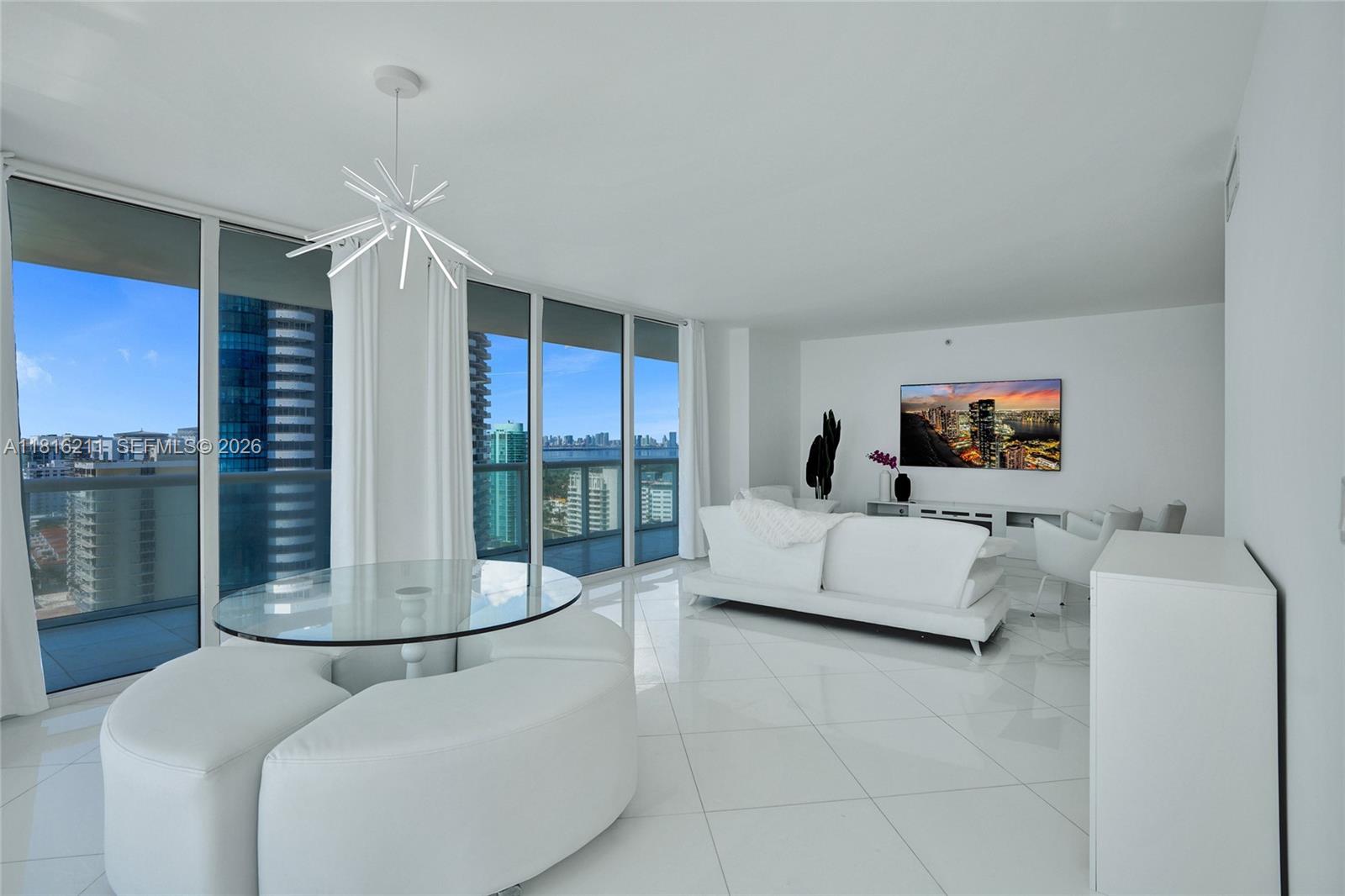 A bright, modern living and dining area features white tile floors, floor-to-ceiling windows, and city views — 6365 Collins Ave # 2403, Miami Beach FL 33141, MIAMI BEACH, FL