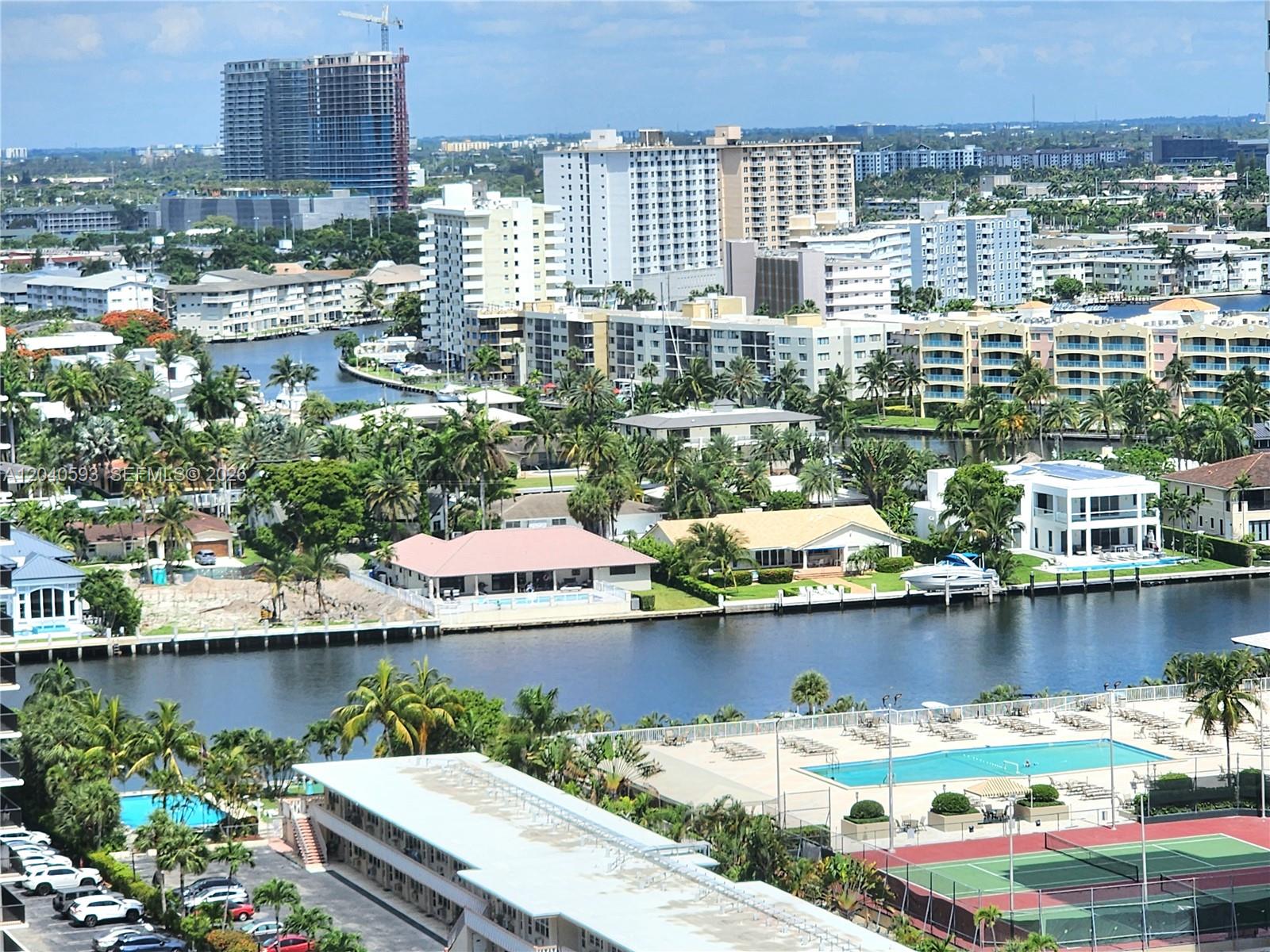 An aerial view shows a canal, residential buildings, swimming pools, and a tennis court — 2030 S Ocean Dr # 401, Hallandale Beach FL 33009, HALLANDALE BEACH, FL