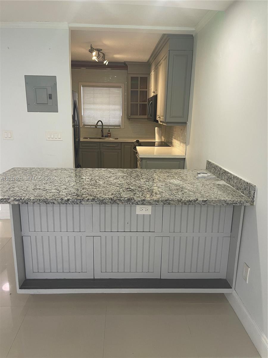 A kitchen features gray cabinets, granite countertops, and a breakfast bar with beadboard paneling — 7505 SW 82nd St # 212, Miami FL 33143, MIAMI, FL