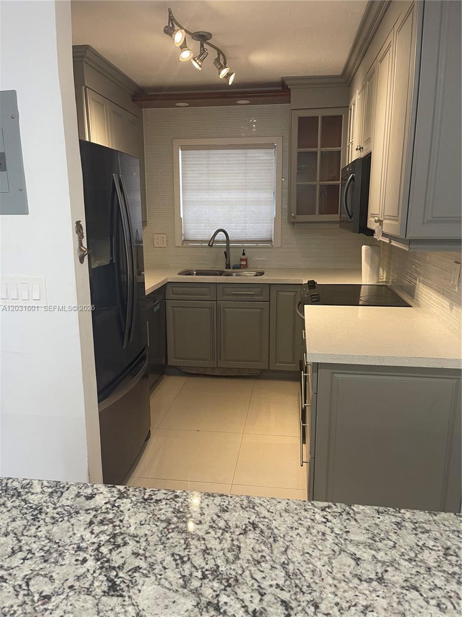 A galley kitchen features gray cabinets, white countertops, a black refrigerator, and tile flooring — 7505 SW 82nd St # 212, Miami FL 33143, MIAMI, FL