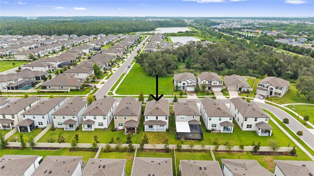 An aerial view shows a suburban neighborhood with a black arrow pointing to a house — 7421 NOTCHED PINE BEND, WESLEY CHAPEL, FL