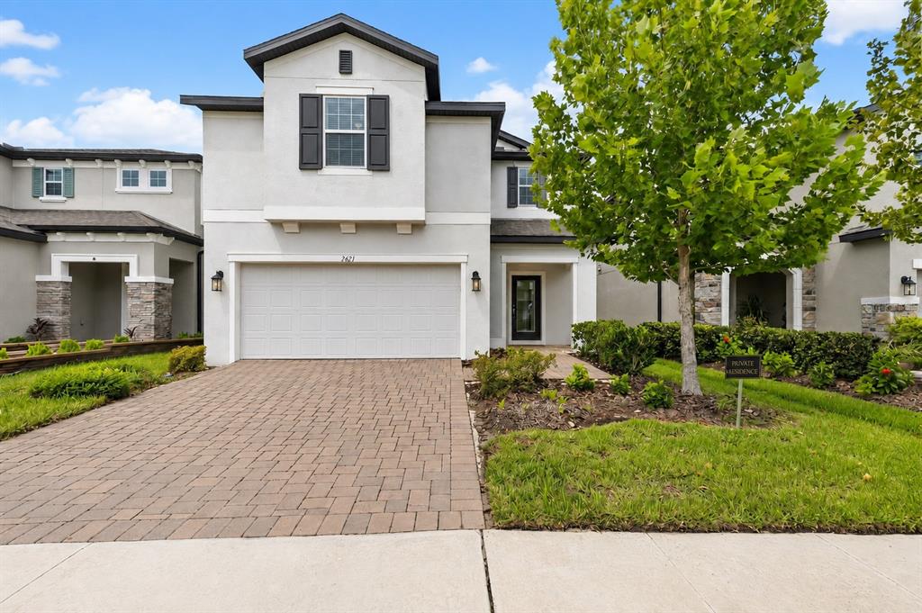 A two-story house with a light-colored stucco exterior, a two-car garage, and a paved driveway — 7421 NOTCHED PINE BEND, WESLEY CHAPEL, FL