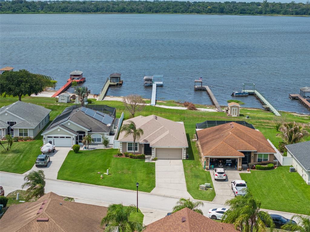 An aerial view shows several suburban houses with driveways and private docks along a lake — 4111 ISLAND LAKES DRIVE, WINTER HAVEN, FL