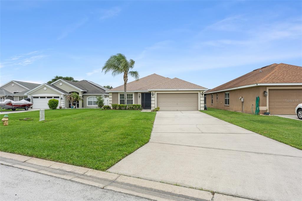 A single-story suburban house with a tan exterior, a two-car garage, and a palm tree — 4111 ISLAND LAKES DRIVE, WINTER HAVEN, FL