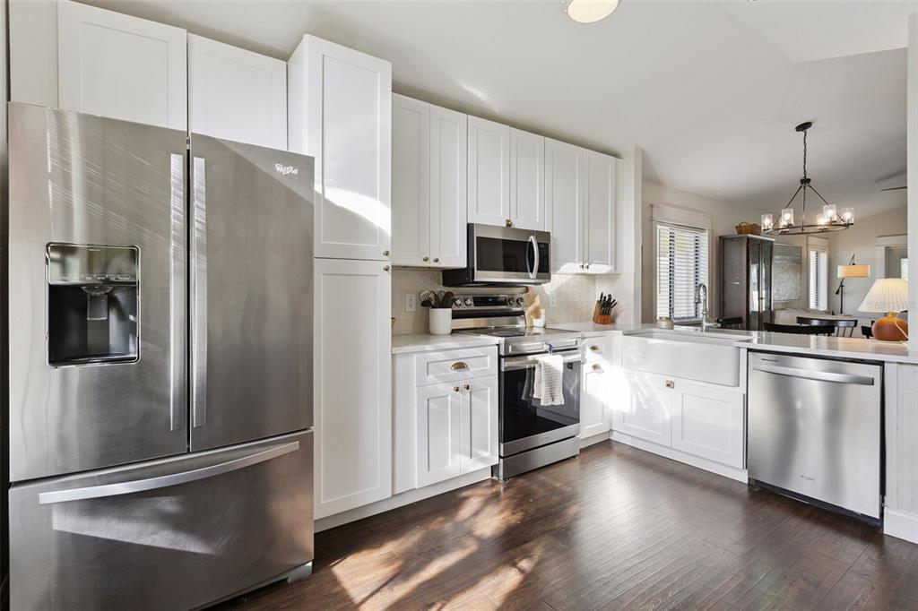A kitchen with white cabinets, stainless steel appliances, a farmhouse sink, and dark wood floors — 1533 SPRINGTIME LOOP, WINTER PARK, FL