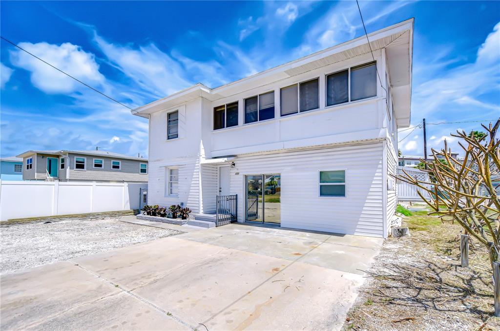 A two-story white house with a concrete driveway and a fenced yard under a blue sky — 150 E MADEIRA AVENUE UNIT 3, MADEIRA BEACH, FL