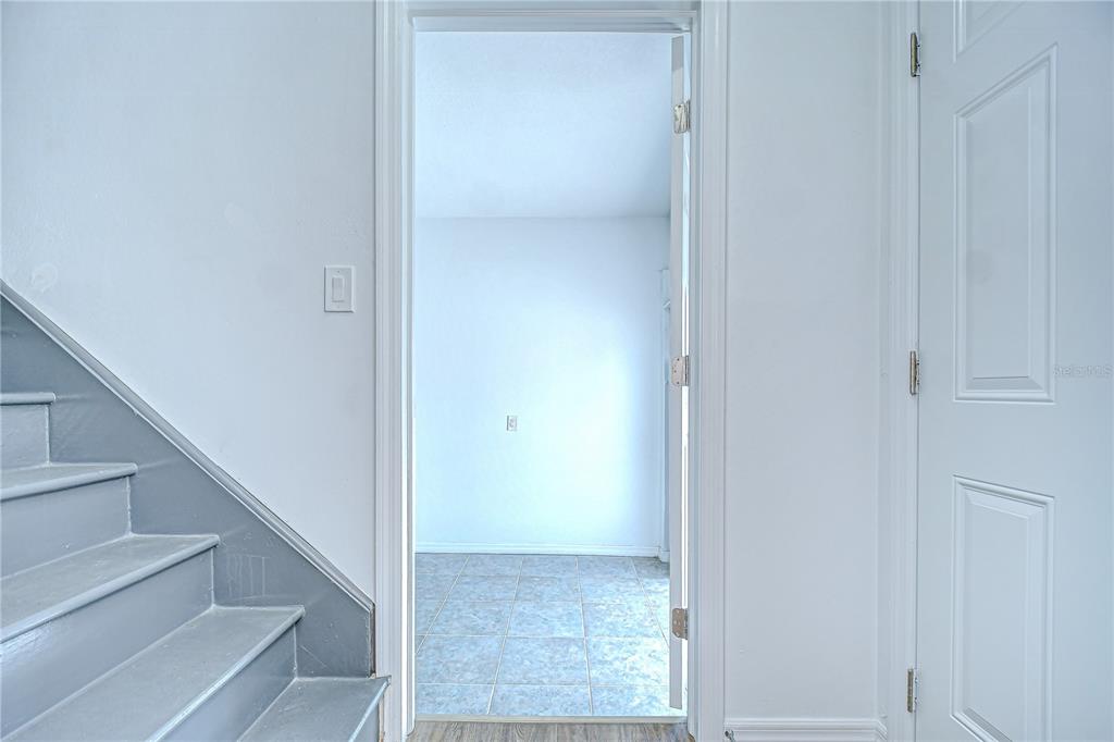A view through a doorway shows a tiled room next to a gray staircase — 150 E MADEIRA AVENUE UNIT 3, MADEIRA BEACH, FL