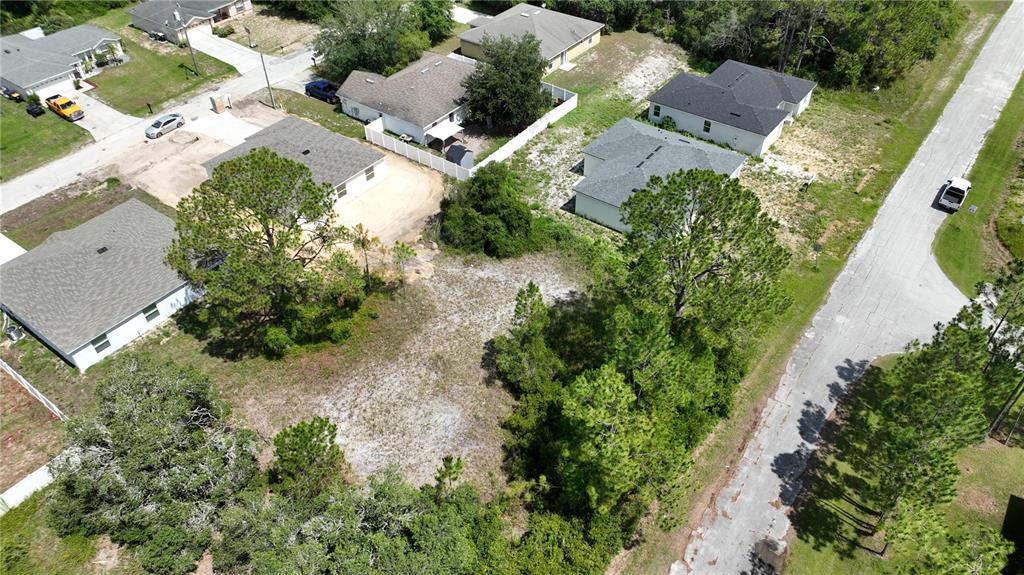 An aerial view shows a vacant residential lot surrounded by several single-family homes and trees — 1212 ATLANTIC WAY, KISSIMMEE, FL