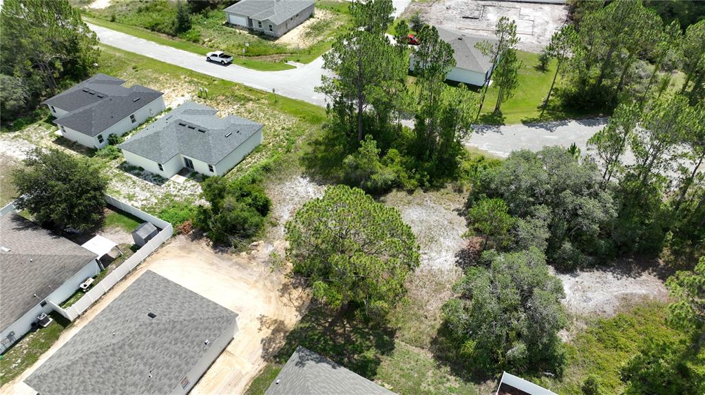 An aerial view shows a vacant residential lot surrounded by houses and trees — 1212 ATLANTIC WAY, KISSIMMEE, FL