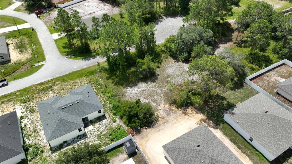 An aerial view shows a vacant residential lot surrounded by houses and trees — 1212 ATLANTIC WAY, KISSIMMEE, FL