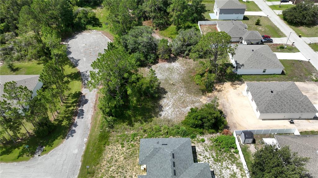 An aerial view shows a vacant residential lot surrounded by trees and neighboring houses — 1212 ATLANTIC WAY, KISSIMMEE, FL