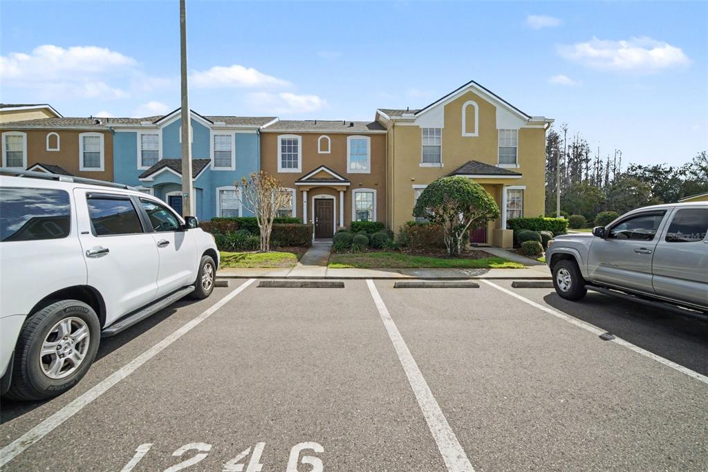 A row of multi-story townhomes with parking spaces in the foreground — 1246 CHARLESWORTH DRIVE, WESLEY CHAPEL, FL