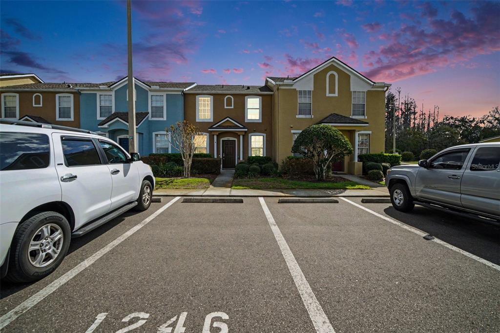 A row of multi-story townhomes with parking spaces in the foreground — 1246 CHARLESWORTH DRIVE, WESLEY CHAPEL, FL