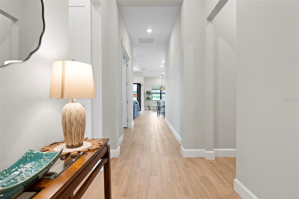 A hallway with light-colored tile flooring leads toward an open-concept living area — 6205 GRANDE TALON LANE, NOKOMIS, FL