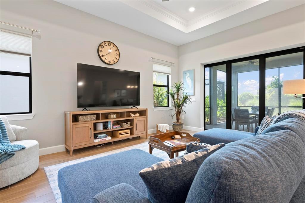 A living room features a blue sectional sofa, a television on a wooden console, and sliding doors — 6205 GRANDE TALON LANE, NOKOMIS, FL