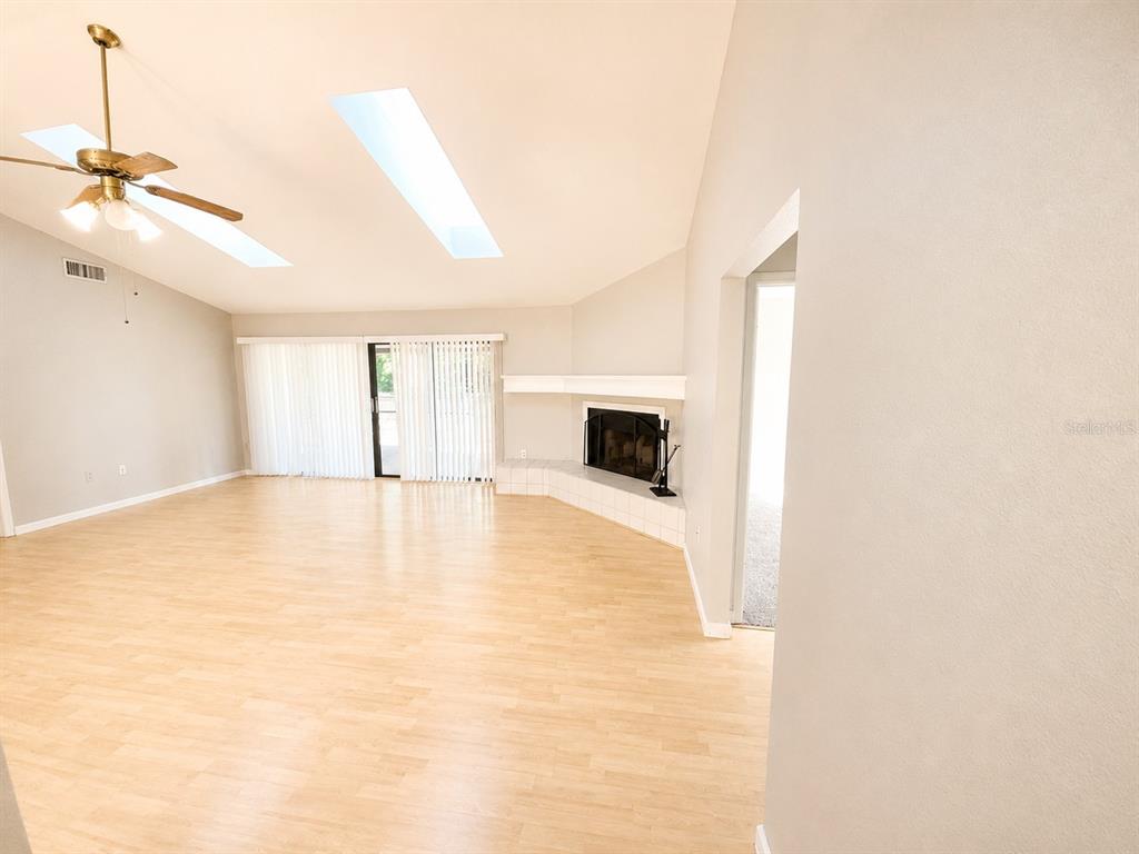 A living room features light wood flooring, a vaulted ceiling with skylights, and a corner fireplace — 700 SOUTH VENICE AVENUE, VENICE, FL