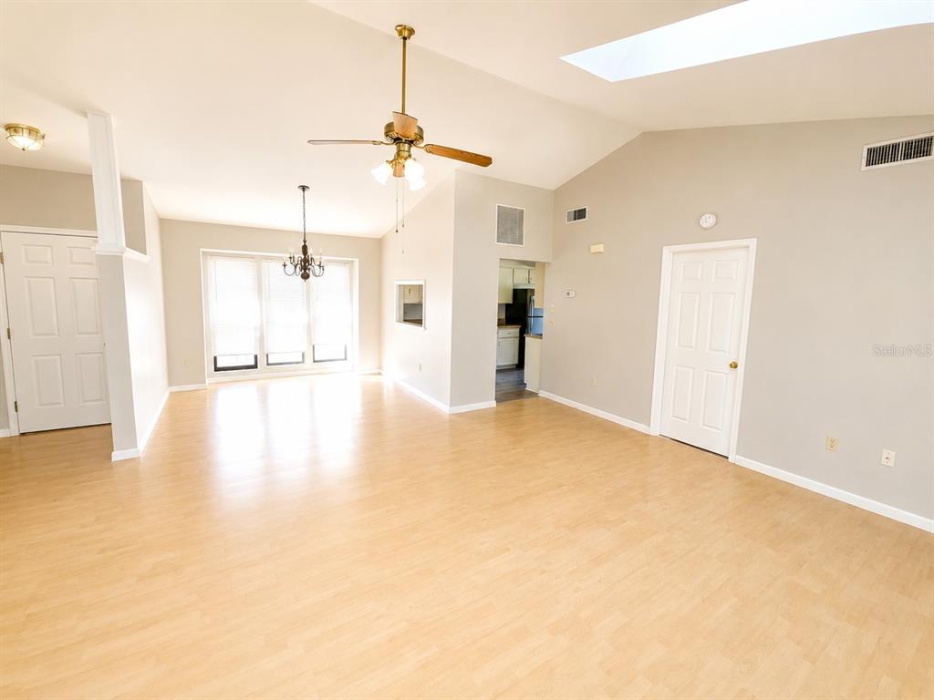 A spacious living room features light wood-look flooring, a vaulted ceiling, and a ceiling fan — 700 SOUTH VENICE AVENUE, VENICE, FL