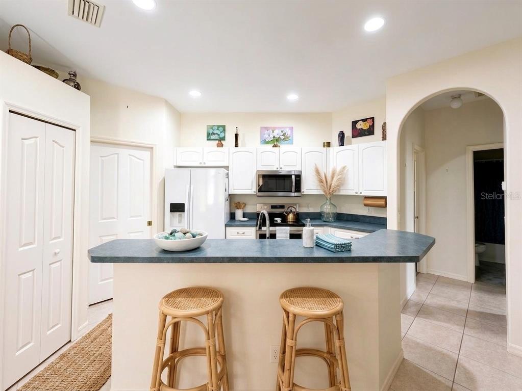 A kitchen with white cabinets, a blue countertop, and two wicker bar stools — 1487 EVANGELINA LANE, NORTH PORT, FL