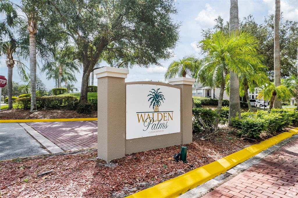 A sign for Walden Palms Condominium stands near a brick driveway surrounded by palm trees — 4760 WALDEN CIRCLE UNIT 5-31, ORLANDO, FL
