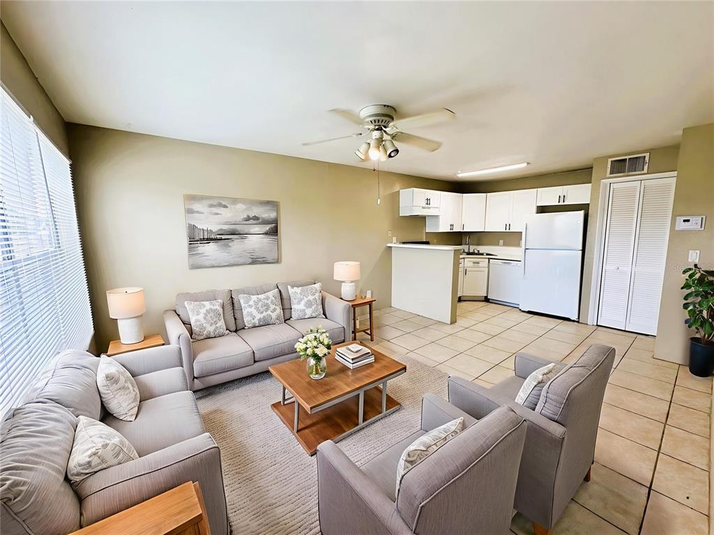 A living room with gray furniture and a rug opens to a kitchen with white cabinets — 4760 WALDEN CIRCLE UNIT 5-31, ORLANDO, FL