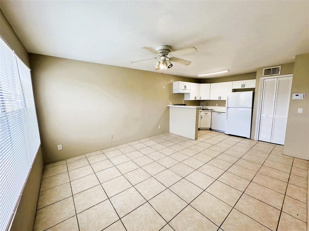 A kitchen with white cabinets and a breakfast bar opens into a tiled dining area — 4760 WALDEN CIRCLE UNIT 5-31, ORLANDO, FL