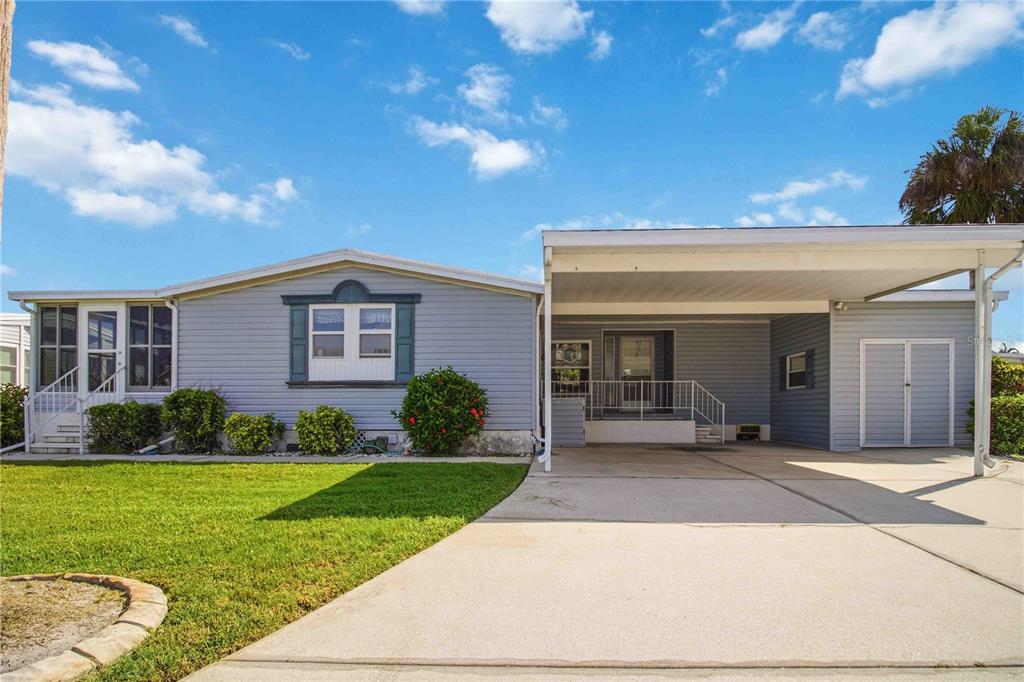 A light blue single-story house features a concrete driveway, a carport, and a front lawn — 8476 IMPERIAL CIRCLE, PALMETTO, FL