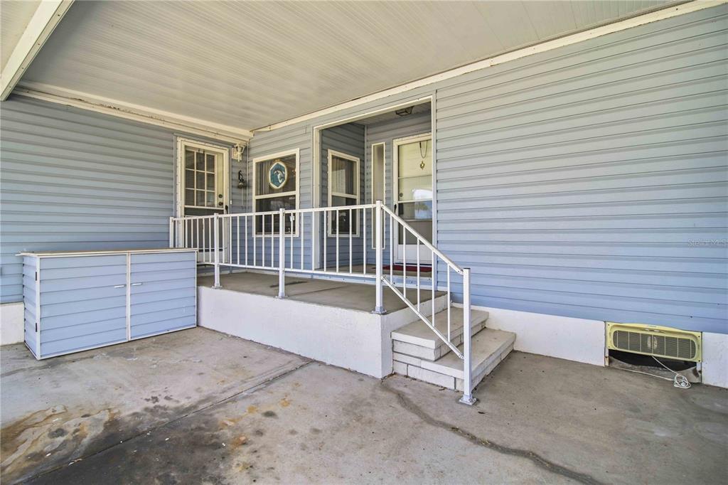 A covered concrete porch features light blue siding, white railings, and two entry doors — 8476 IMPERIAL CIRCLE, PALMETTO, FL