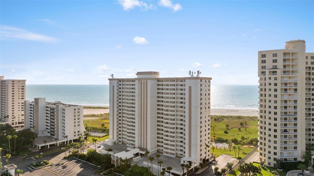An aerial view shows three high-rise condominium buildings situated along a sandy beach — 1230 GULF BLVD UNIT 1204, CLEARWATER, FL