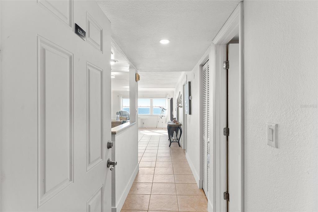 An entryway leads into a tiled hallway with a view of the ocean beyond — 1230 GULF BLVD UNIT 1204, CLEARWATER, FL