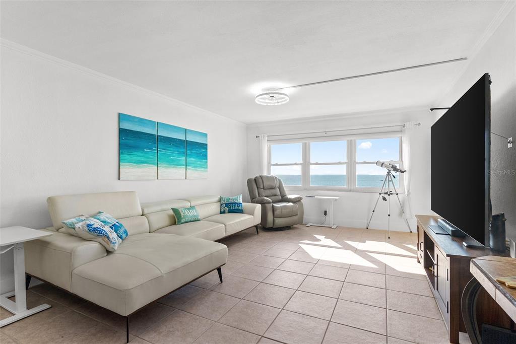 A living room with a white sectional sofa, a recliner, and a view of the ocean — 1230 GULF BLVD UNIT 1204, CLEARWATER, FL