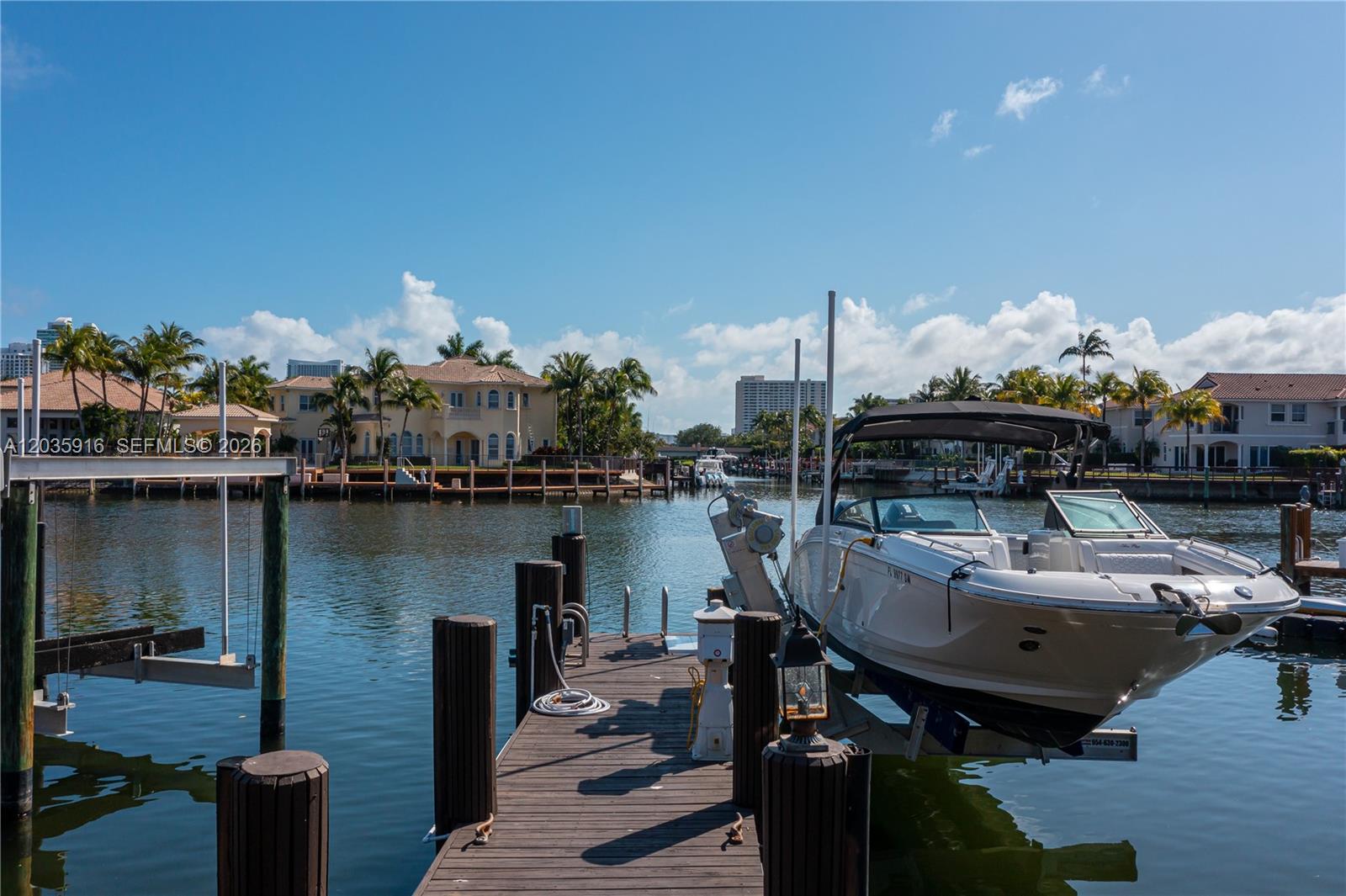 A white motorboat sits on a lift at a wooden dock on a canal — 954 Sanibel Dr # 954, Hollywood FL 33019, HOLLYWOOD, FL