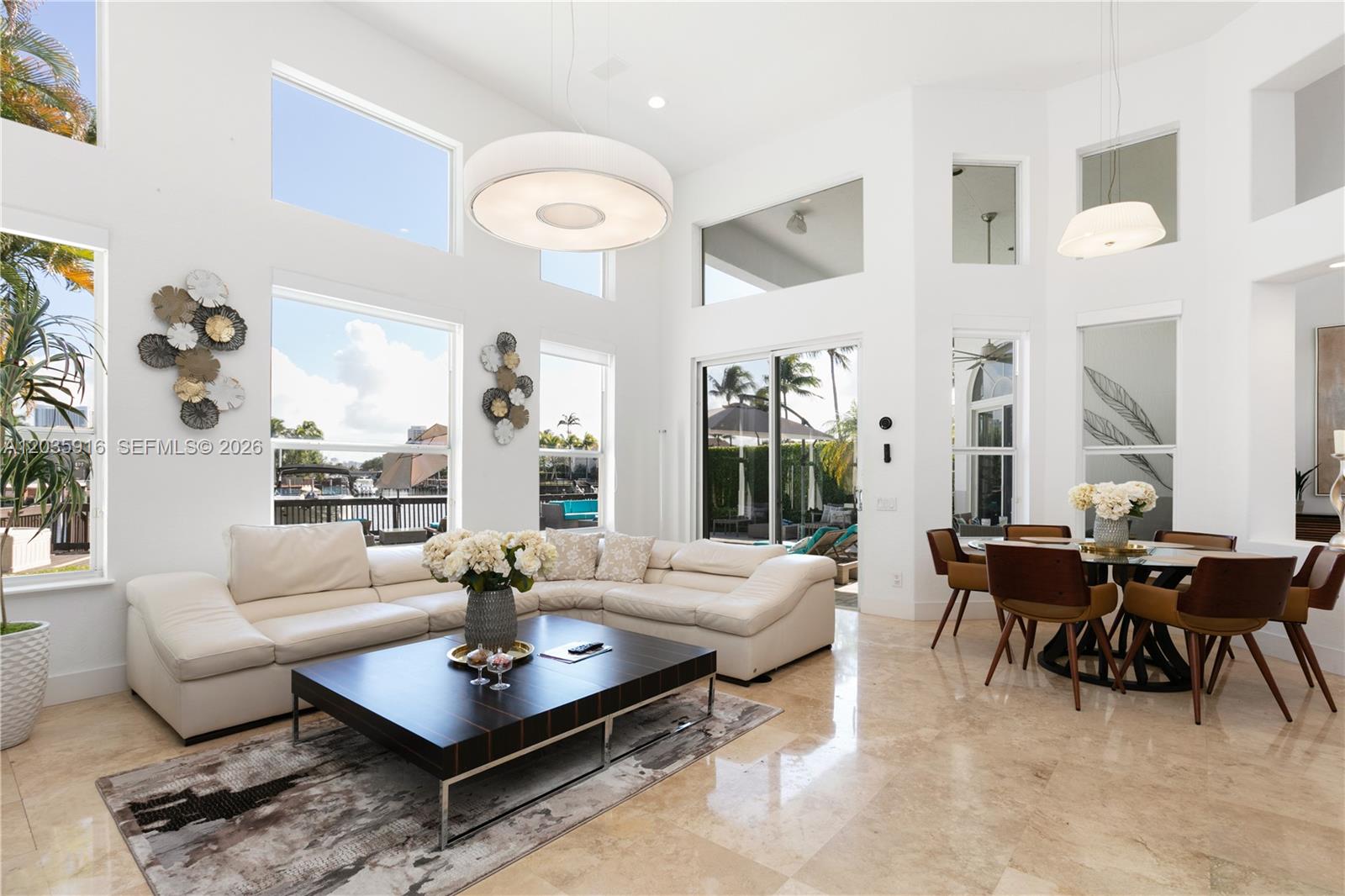A bright, high-ceilinged living and dining area features white leather furniture and marble flooring — 954 Sanibel Dr # 954, Hollywood FL 33019, HOLLYWOOD, FL