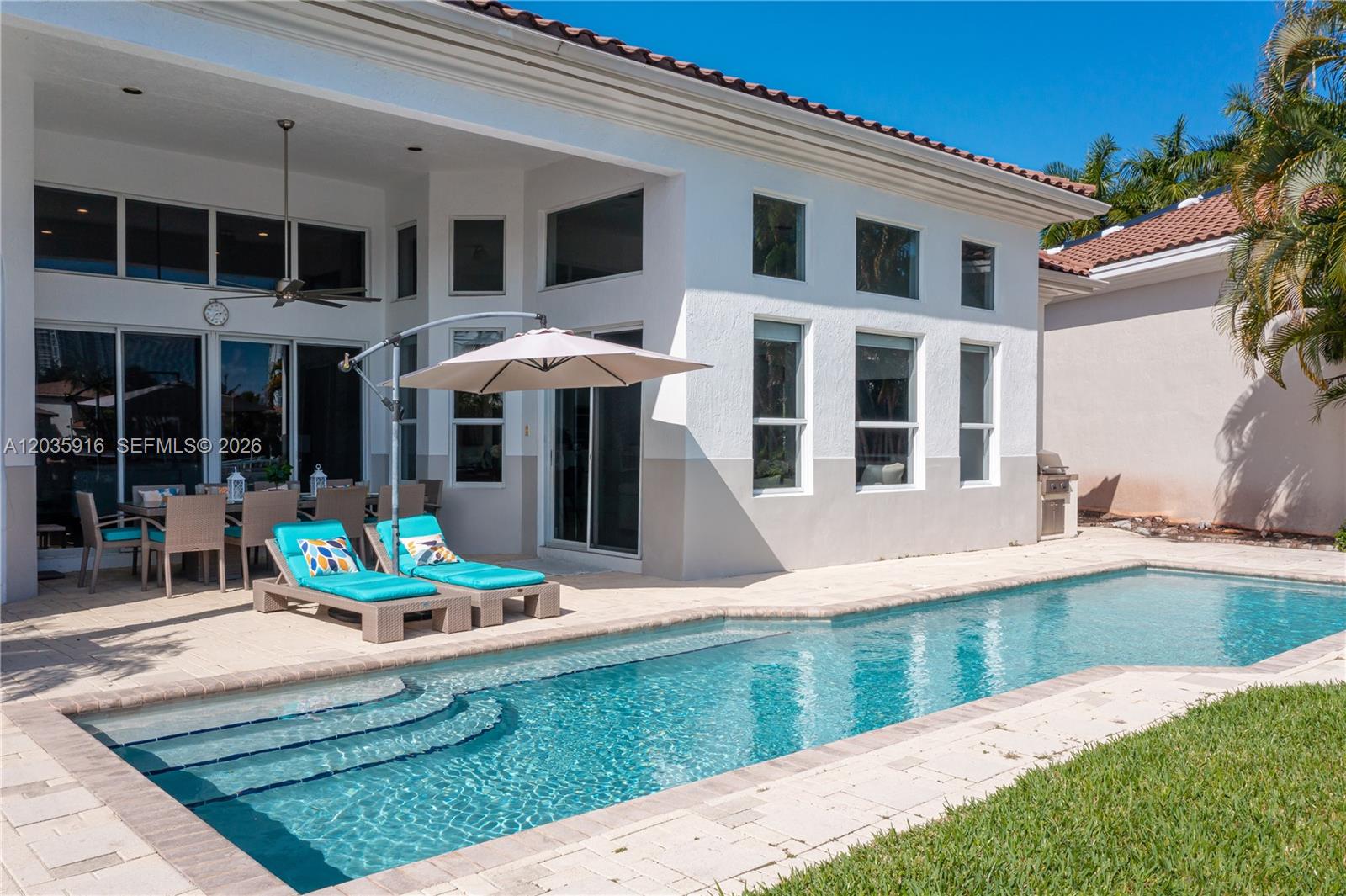 A backyard patio features a swimming pool, lounge chairs, an umbrella, and outdoor dining furniture — 954 Sanibel Dr # 954, Hollywood FL 33019, HOLLYWOOD, FL