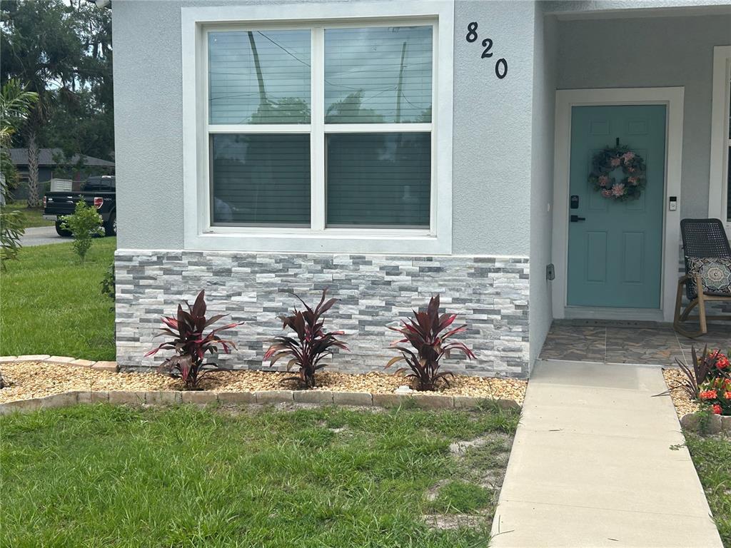 The exterior of a house features a light blue door, stone veneer siding, and landscaping — 820 PECAN AVENUE, SANFORD, FL