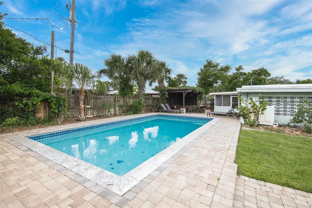 A rectangular swimming pool sits in a backyard with a paver patio and wooden fence — 159 SOUTHWIND CIRCLE, ST AUGUSTINE, FL