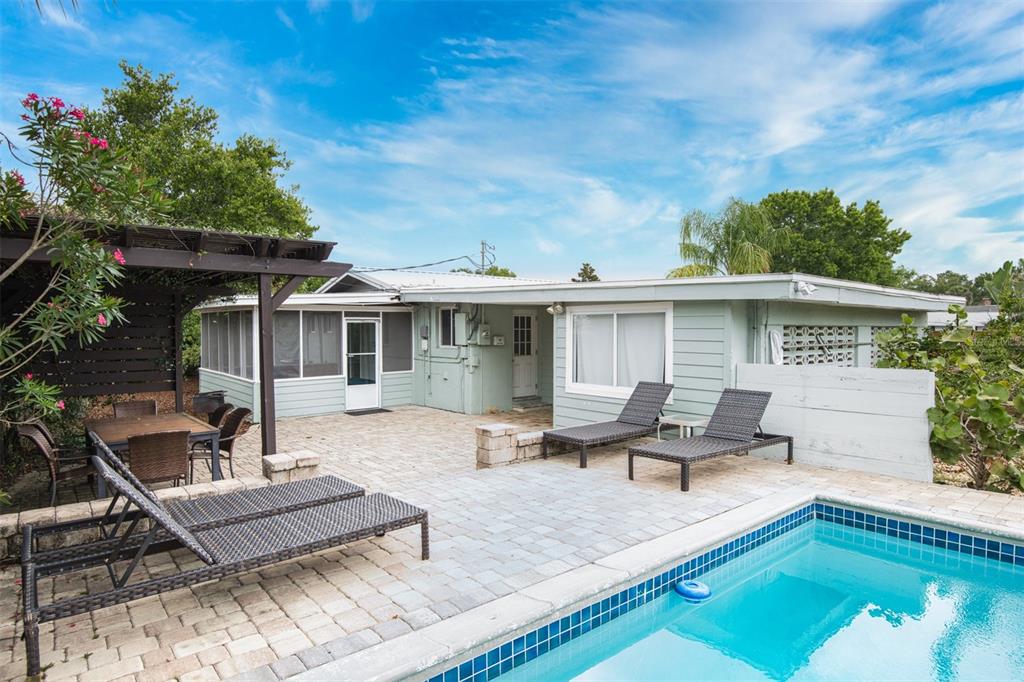 A backyard patio features a swimming pool, lounge chairs, a dining area, and a pergola — 159 SOUTHWIND CIRCLE, ST AUGUSTINE, FL