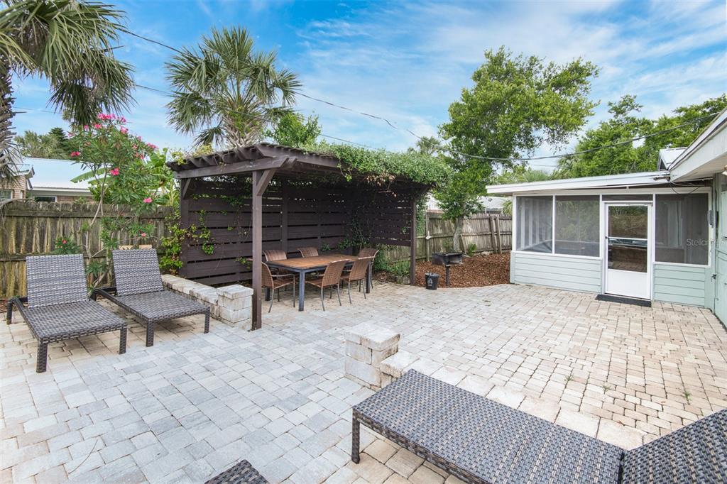 A backyard patio features a pergola, dining set, lounge chairs, and a screened-in porch — 159 SOUTHWIND CIRCLE, ST AUGUSTINE, FL