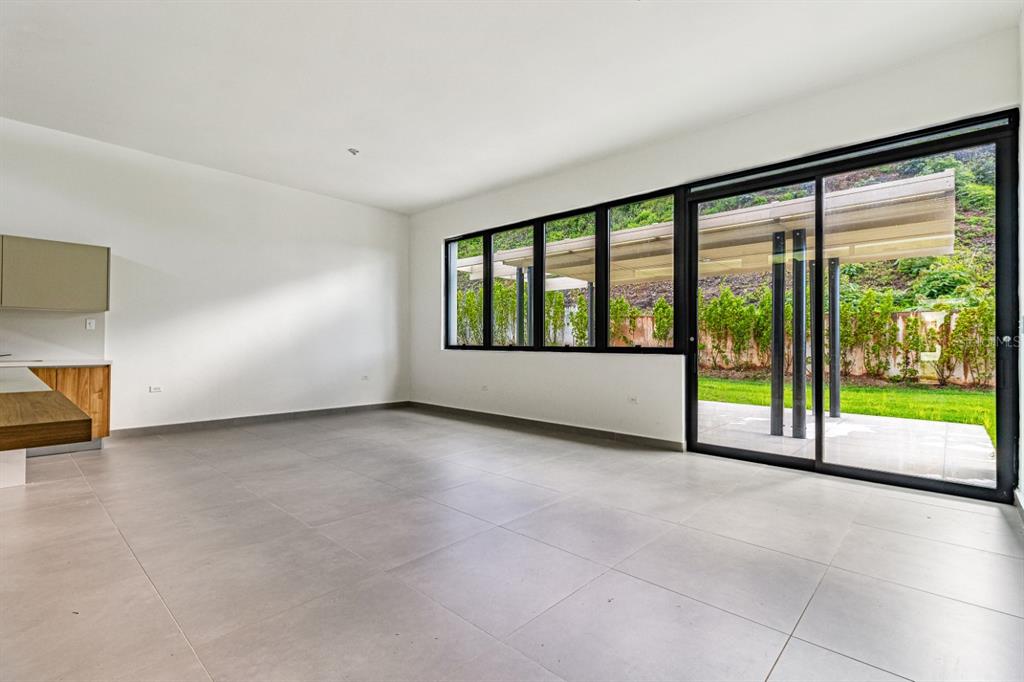 An empty room with large windows, sliding glass doors, and light-colored tile flooring — 238 URB. MONTEAZUL, GUAYNABO, PR